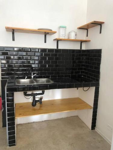 ein Badezimmer mit einem Waschbecken und einer schwarzen Backsteinwand in der Unterkunft Universo in Buenos Aires
