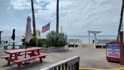 サウス・パドレ・アイランドにあるSandcastle 201B Condominium Condoのビーチの横にあるピクニックテーブルとパラソル