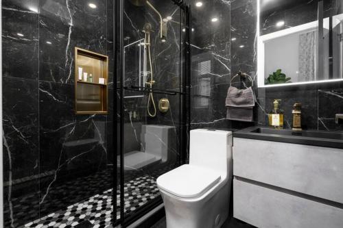 a black bathroom with a toilet and a shower at Downtown Luxe: Metro, King Bed, Parking, Sleeps 6 in Montréal