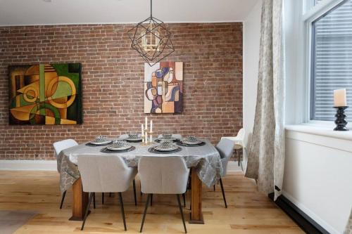 a dining room with a table with chairs and a brick wall at Downtown Luxe: Metro, King Bed, Parking, Sleeps 6 in Montréal