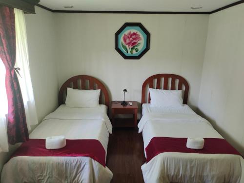 2 łóżka w małym pokoju z oknem w obiekcie Tropical Paradise Retirement Village Inc w mieście Sawat