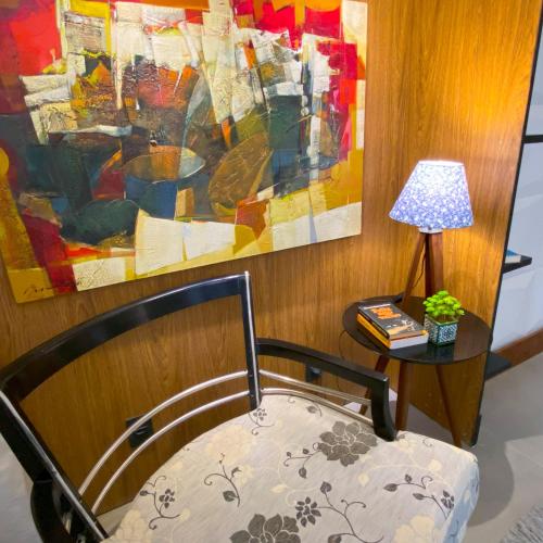 a chair and a table with a lamp and a painting at Rio Holiday Boutique Hotel in Niterói