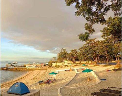 a sandy beach with green umbrellas and the water at Mactan Newtown Beach Condo in Mactan