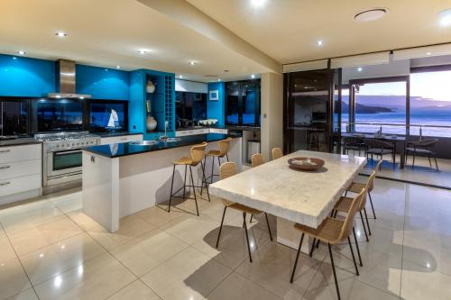 a kitchen with blue walls and a table with chairs at Edge Apartments on Hamilton Island by HIHA in Hamilton Island