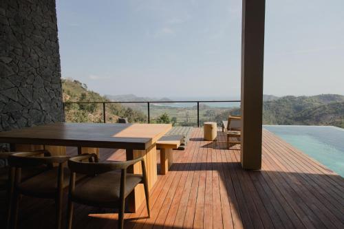 a wooden deck with a table and chairs and a pool at DUNIA LOMBOK - Villas with Ocean View in Selong Belanak