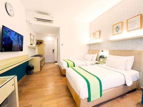 a hotel room with two beds and a tv at Hotel Wisata Niaga Campus in Purwokerto