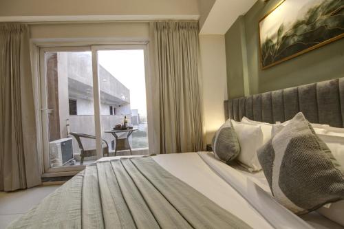 a bedroom with a bed and a large window at Saltstayz Premier - Golf Course Extension Road in Gurgaon
