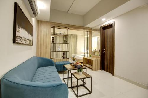 a living room with a blue couch and a bathroom at Saltstayz Premier - Golf Course Extension Road in Gurgaon