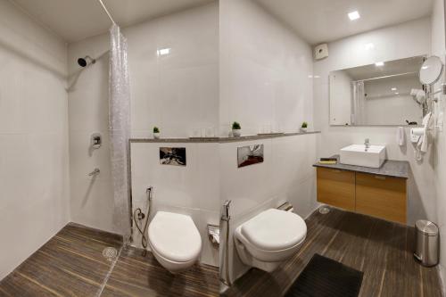 a white bathroom with a toilet and a sink at Saltstayz Premier - Golf Course Extension Road in Gurgaon