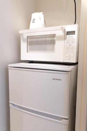 a microwave sitting on top of a refrigerator at SLEEPLAB THE STAY 渋谷 -睡眠特化型Hotel- in Tokyo