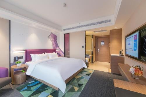 Hampton by Hilton Zhengzhou High-Tech Zone في تشنغتشو: غرفة نوم بسرير كبير وتلفزيون