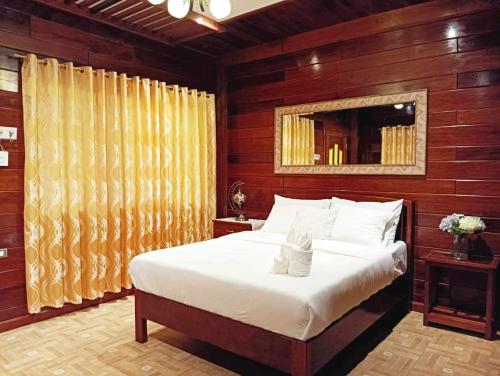 a bedroom with a large white bed with wooden walls at Theresa's Pension House in San Vicente