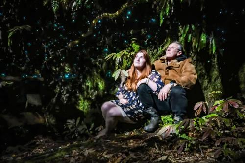 een man en een vrouw zittend op een rots in de jungle bij Te Tiro Accommodation in Waitomo Caves