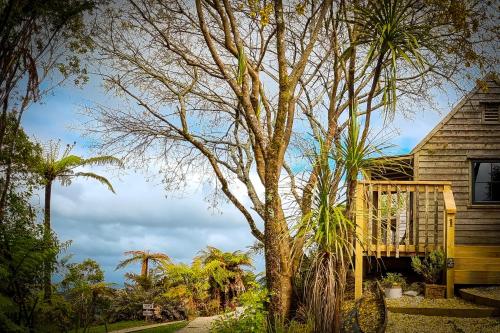 a tree in front of a house with a deck at Te Tiro Accommodation in Waitomo Caves