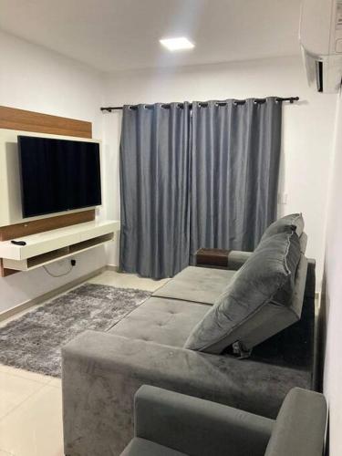 Il comprend un salon doté d'un canapé et d'une télévision à écran plat. dans l'établissement Belíssimo apartamento com vista praia, à Praia Grande