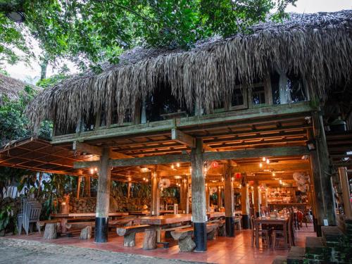 a restaurant with wooden tables and a thatched roof at Pu Luong Jungle Lodge in Pu Luong