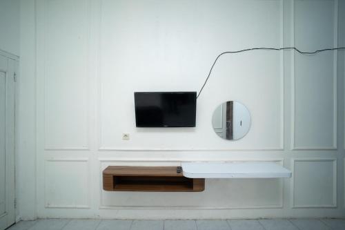 einen TV an einer weißen Wand mit einem Spiegel in der Unterkunft KS Hotel in Cilacap