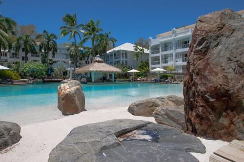 ein Pool mit Felsen vor einem Hotel in der Unterkunft Private Ground Floor Apartment Beach Club Palm Cove in Palm Cove