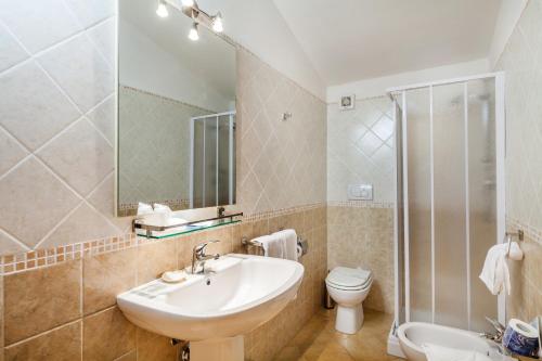 a bathroom with a sink and a toilet and a mirror at Hotel Petri Marini in Aglientu