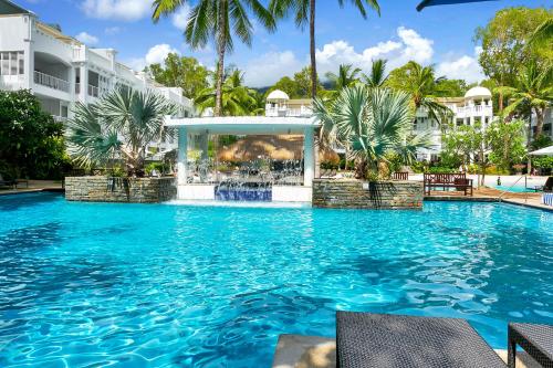 einen Pool in einem Resort mit Palmen und einem Pavillon in der Unterkunft Private Ground Floor Apartment Beach Club Palm Cove in Palm Cove