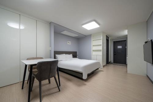 Myeongga Ubleth Hotel في يوسو: غرفة نوم بسرير وطاولة وتلفزيون