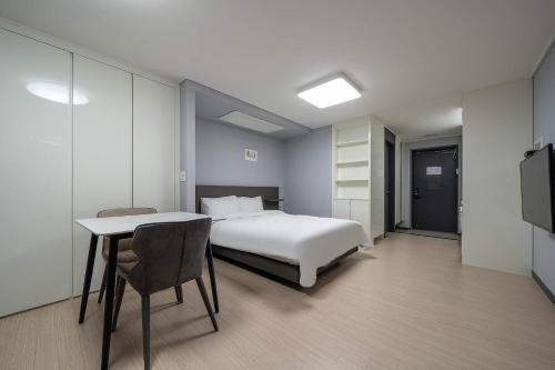 - une chambre avec un lit, une table et une télévision dans l'établissement Myeongga Ubleth Hotel, à Yeosu