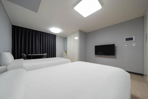a hotel room with two beds and a television at Myeongga Ubleth Hotel in Yeosu