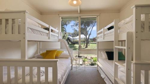 a bedroom with white bunk beds and a window at Nakarra in Lake Tyers