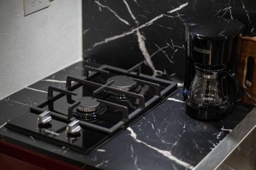 a black stove top with a coffee maker on a counter at Génesis Apt 2 in Levittown