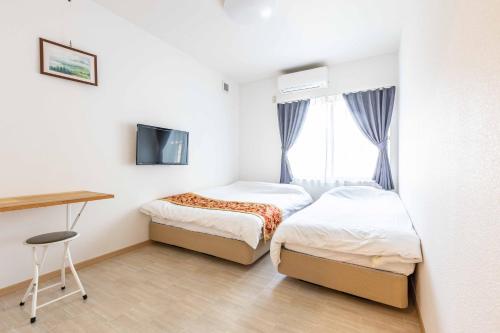 a bedroom with two beds and a desk and a television at add-Hostel Uji Cha-gan-ju-tei in Uji