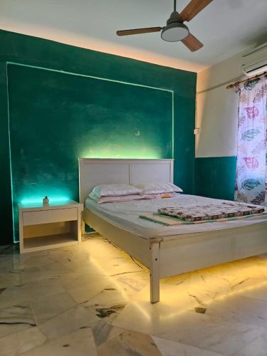a bedroom with a bed and a green wall at PakYa Homestay in Kampong Padang Jawa