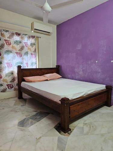 a bed in a room with a purple wall at PakYa Homestay in Kampong Padang Jawa