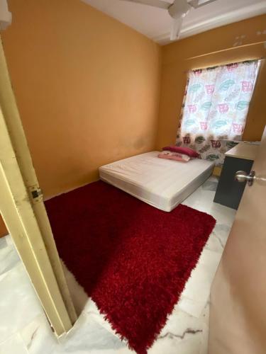 a small room with a red rug on a bed at PakYa Homestay in Kampong Padang Jawa