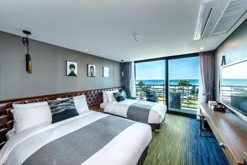 Habitación de hotel con 2 camas y ventana grande. en Marevo Beach Hotel en Jeju