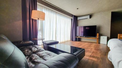 a living room with a leather couch and a television at Business Resort Kyuan in Oita