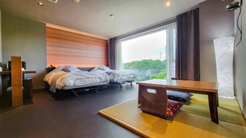 a bedroom with a bed and a desk and a window at Business Resort Kyuan in Oita