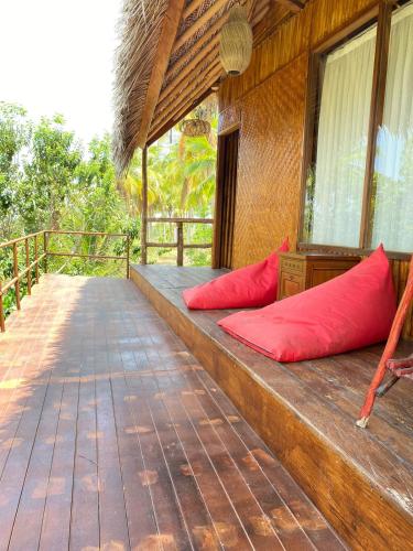 a porch of a house with red pillows on it at Gading Tree House in Nusa Penida