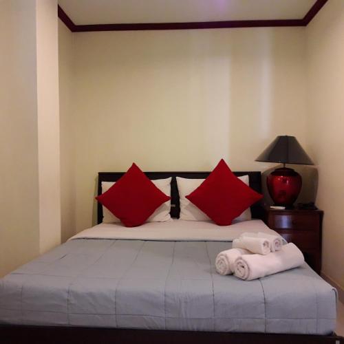 a bedroom with a bed with red pillows and towels at Prince Edouard Apartments & Resort Patong Beach Phuket in Patong Beach