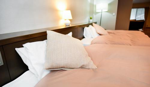 two beds in a hotel room with pillows on them at Resort Yufuin - Grandpia Resort Yufuin in Yufuin