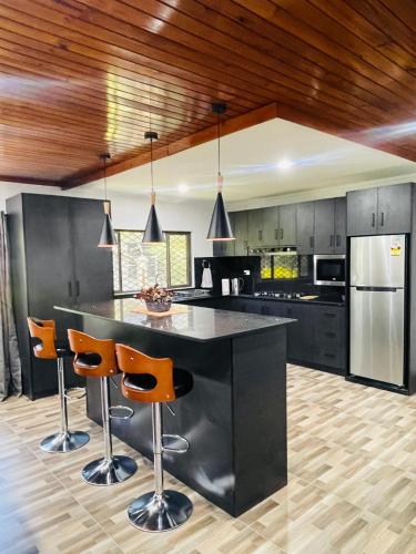 a kitchen with a large black island with bar stools at Blissful Calm in Nadi
