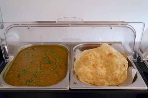 a plastic container with a meal of soup and a tortilla at Hotel Asrani International in Secunderabad