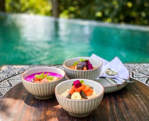 three bowls of food on a table near a pool at Villa Gaya Ubud in Ubud