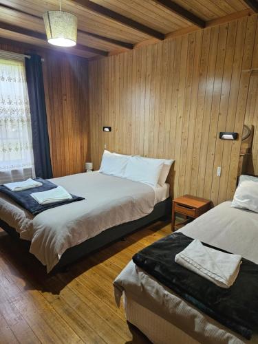 two beds in a room with wooden walls and wooden floors at Lake Leake Inn in Lake Leake