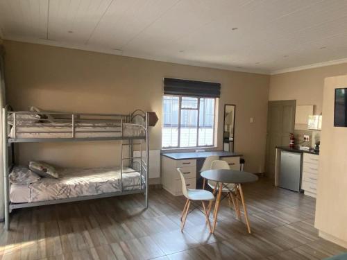 a room with bunk beds and a table and chairs at Aloe Guest Rooms in Bloemfontein