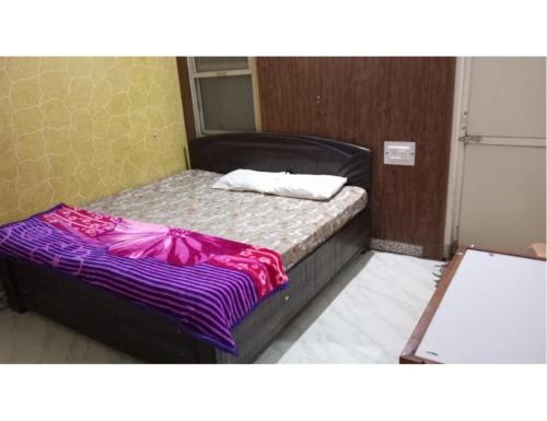 a small bed in a room with a purple blanket at Hotel Sanginee, Maheshwar in Maheshwar