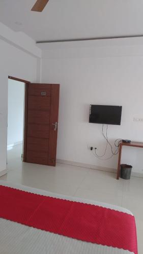 a room with a red rug and a tv on a wall at PPH Living B S K in Bengaluru