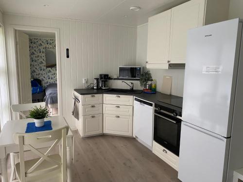 a kitchen with white cabinets and a white refrigerator at Rosendal Apartments Motellet in Rosendal