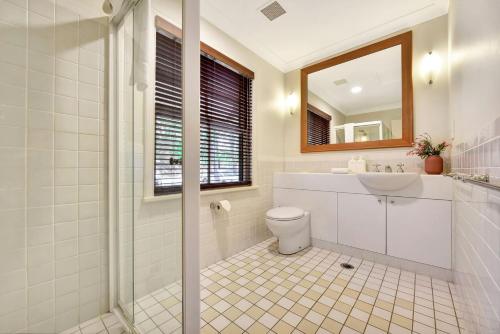 uma casa de banho com um WC, um lavatório e um espelho. em Villa 2br Madeira Villa located within Cypress Lakes Resort em Pokolbin