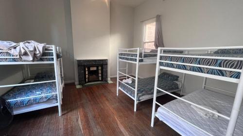 a room with three bunk beds and a fireplace at Beachside Budget Rooms in Kiama