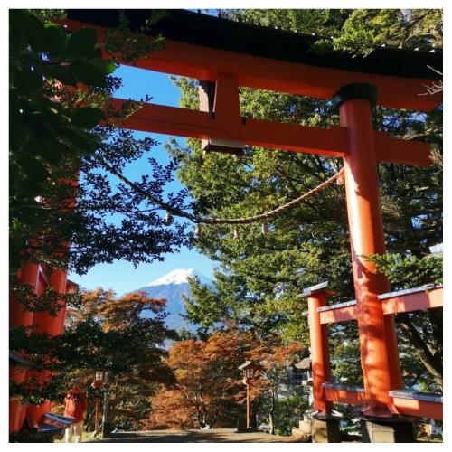 an orange torii gate with a mountain in the background at 福寿苑　Fukujuen in Oshino